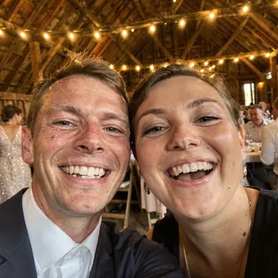 Man en vrouw maken lachend een selfie onder de lichtjes in een schuur