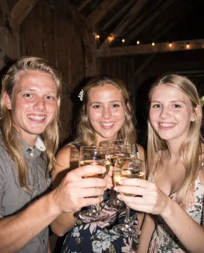 Drie jonge vrienden proosten met wijn in een houten schuur