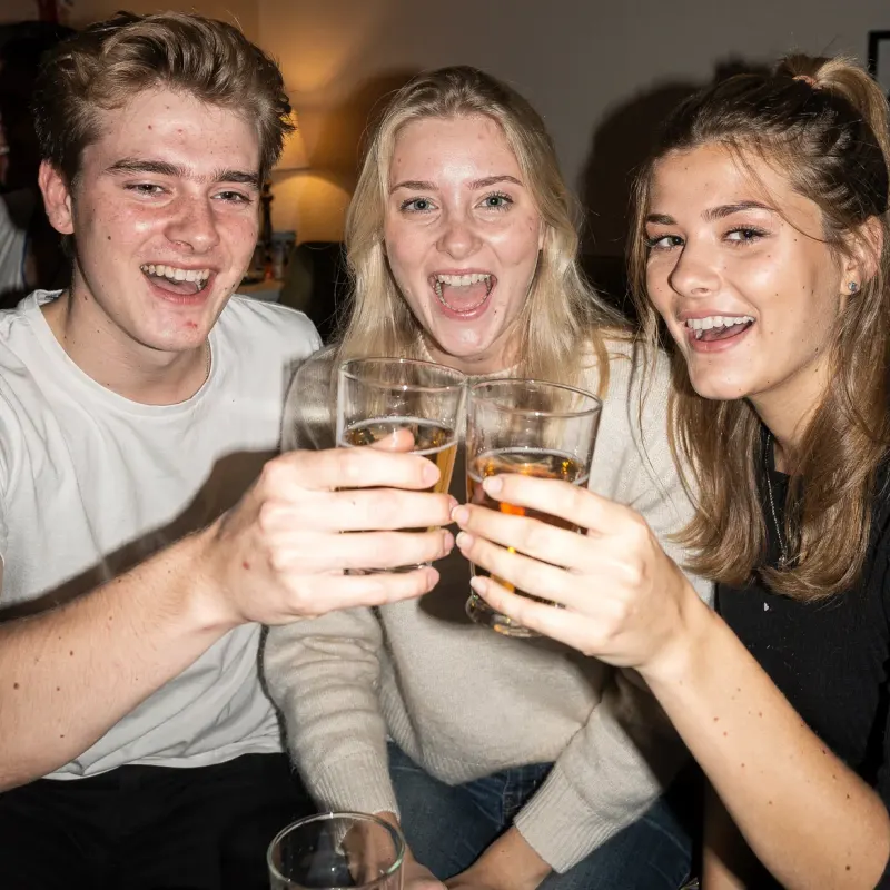 Drie vrienden proosten lachend op een huisfeest