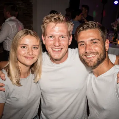 Drie vrienden arm in arm op een bruiloftsfeest